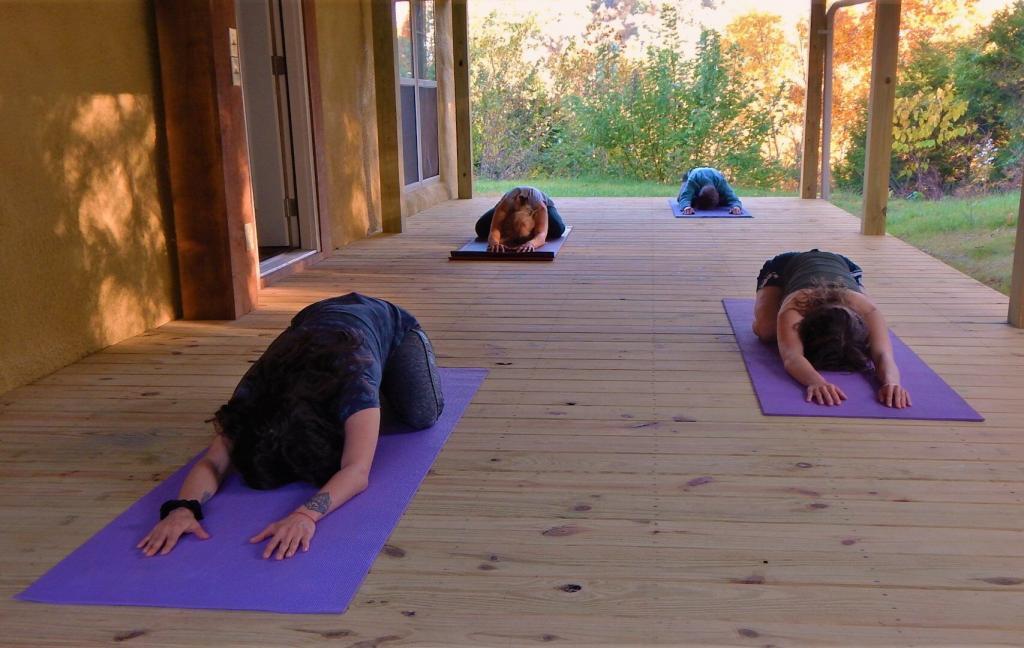 yoga on large covered porch at Straw Bale Lodge